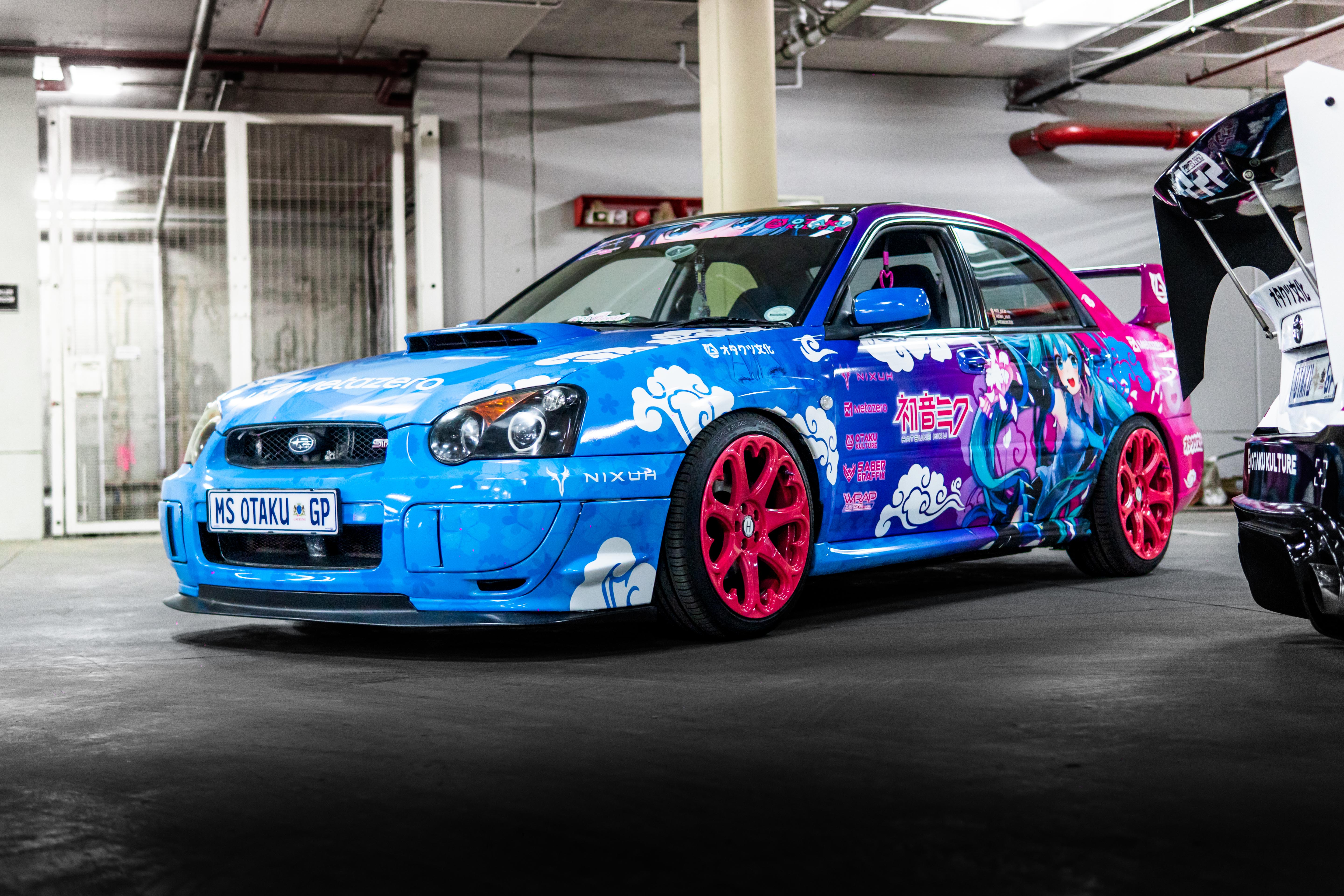 Colorful car with anime-style graphics in a garage setting