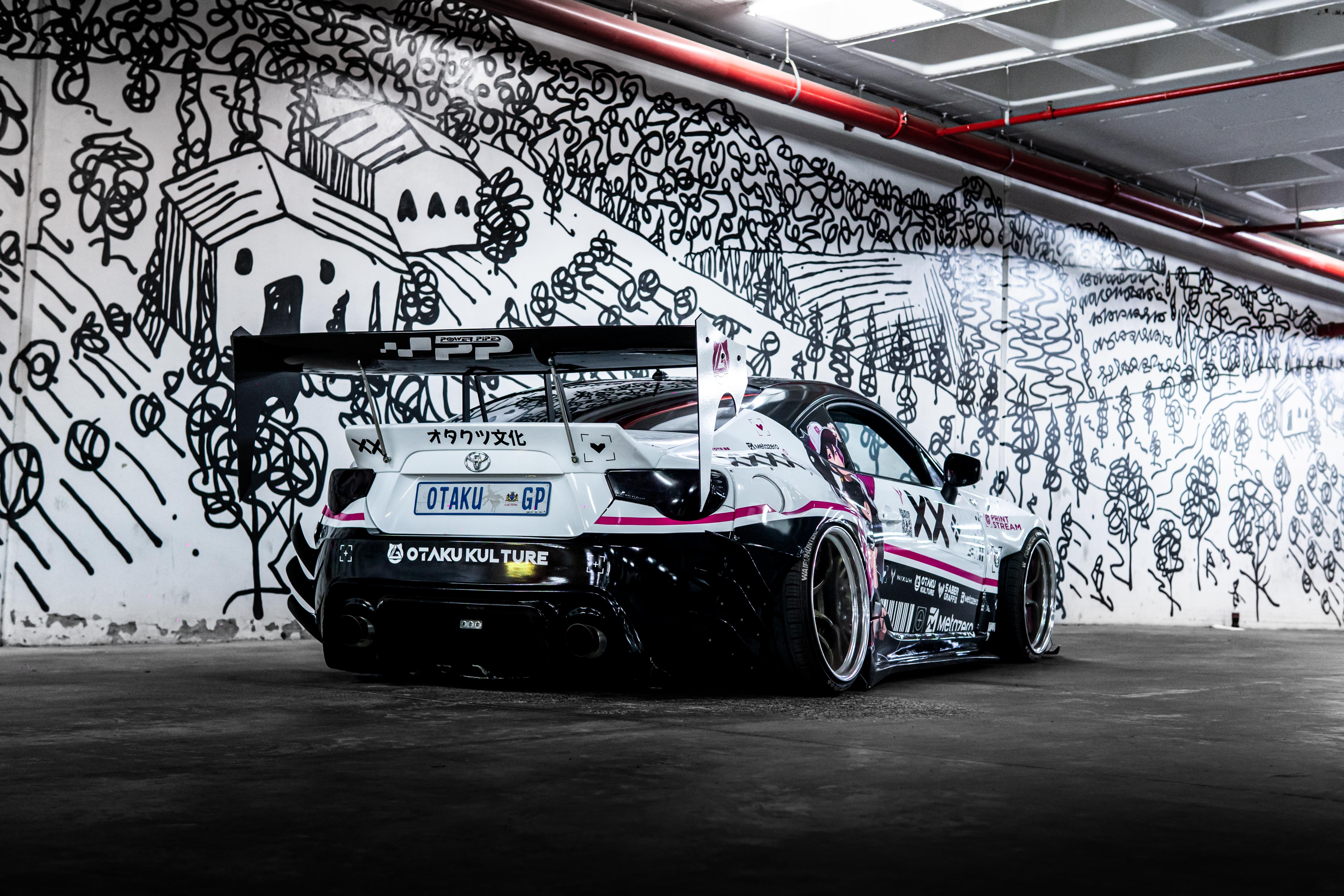 Car with racing livery in a garage with artistic wall designs